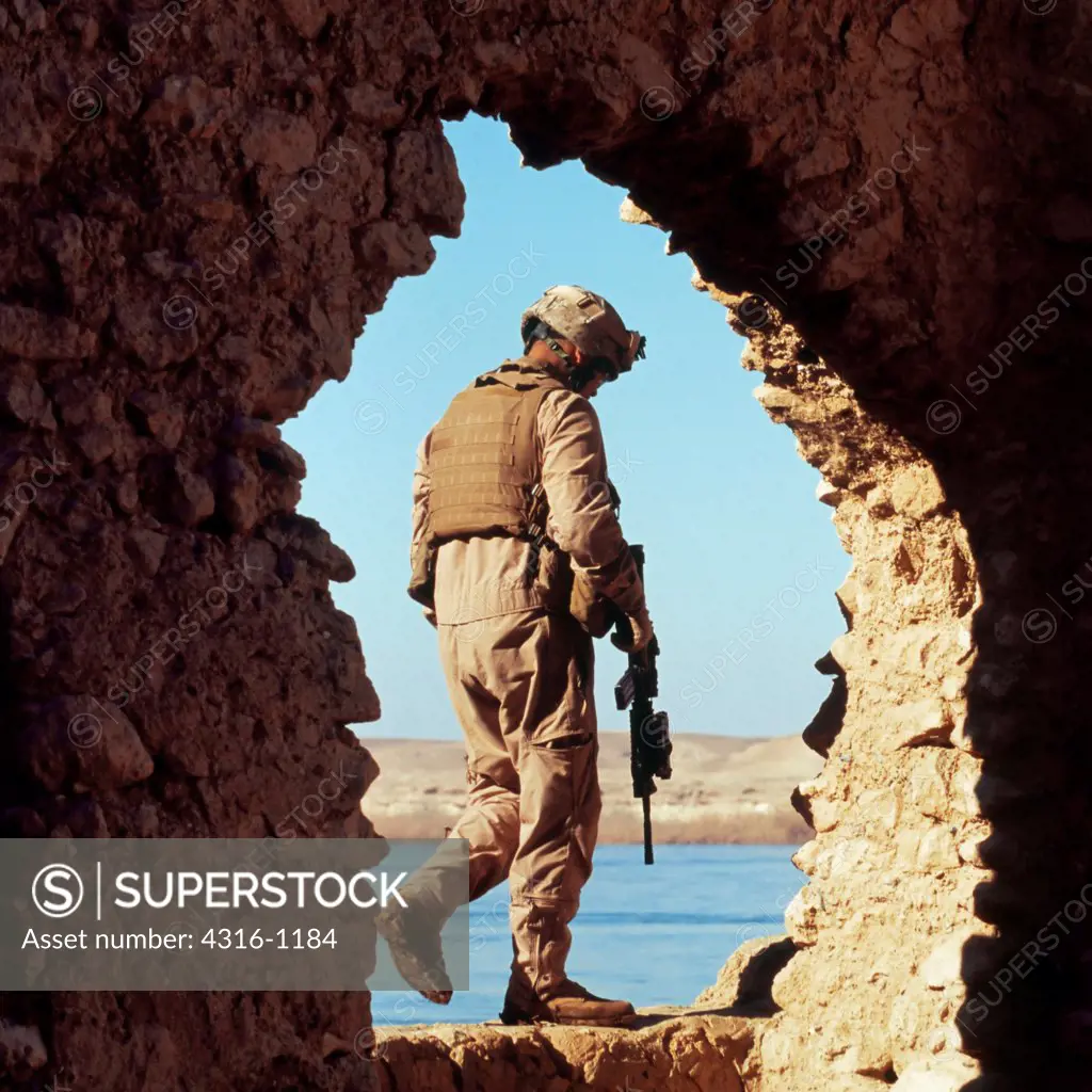 Ancient Stone House Frames a Patrolling US Marine Along The Banks of The Euphrates River
