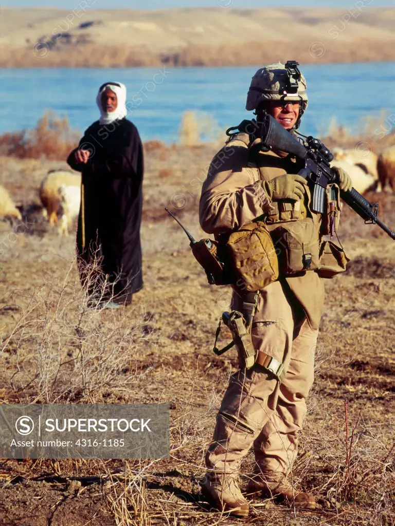 A US Marine Walks Past an Iraqi Sheep Herder and His Flock During a Combat Operation Along The Banks of the Euphrates River