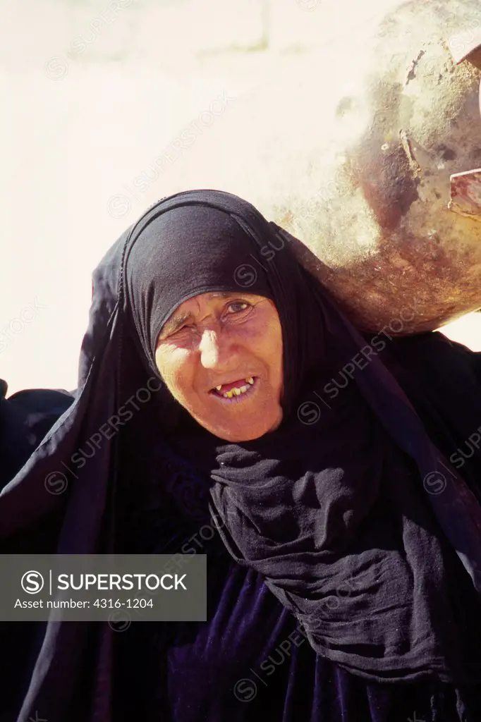 An Iraqi Woman Carries a Tank of Propane on Her Back Near Haditha, Iraq