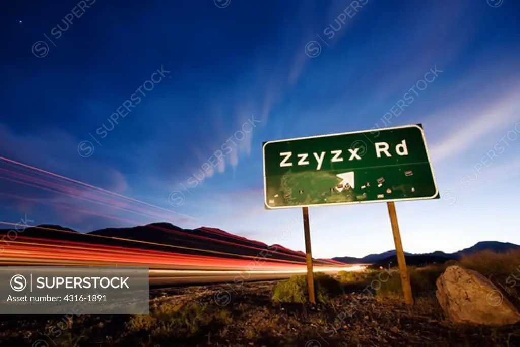 Cars Speed Past the  Zzyzx Road Sign on I-15