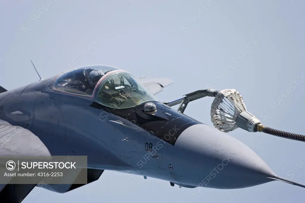 A Malaysian Air Force Mig-29 during maneuvers of its in-flight refueling probe into the 'basket' at the end of a refueling hose from a United States Marine Corps KC-130J Super Hercules high above the South China Sea, Malaysia.