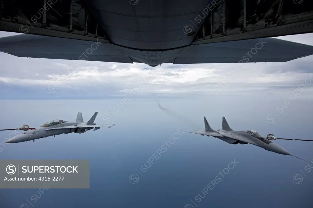 A view from the tail section of a United States Marine Corps KC-130J Super Hercules as it refuels an American F/A-18D Hornet (left) and  a Malaysian Mig-29 Fulcrum high over the South China Sea, Malaysia.