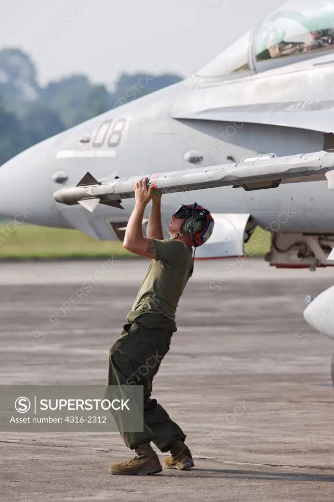 A United States Marine Corps weapons technician arms an Aim-9x Sidewinder missile mounted on an F/A-18D Hornet at Kuantan Air Base, Malaysia.