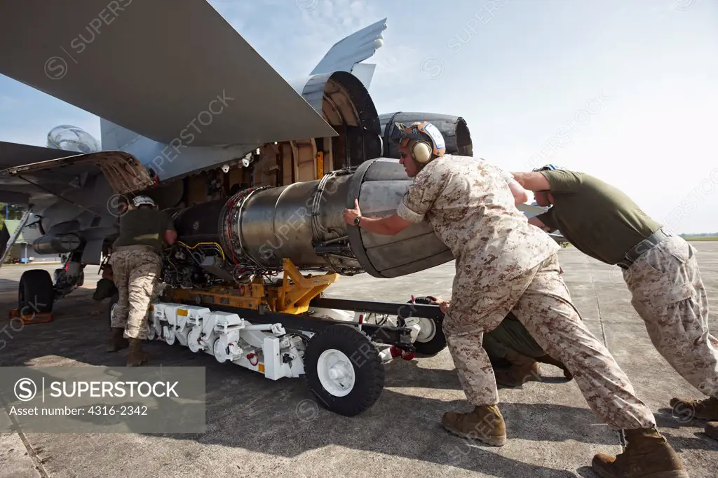 United States Marine Corps aircraft maintainers install a new engine on an F/A-18D Hornet at Kuantan Air Base, Malaysia.