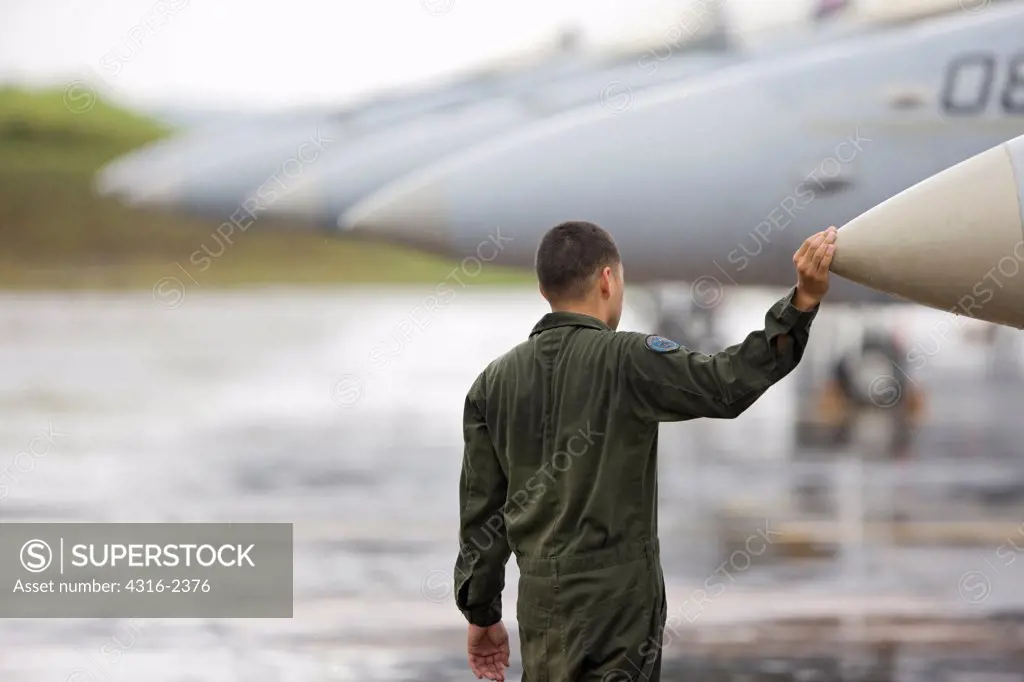 A United States Marine Corps aviator, during a light rain storm, inspects an F/A-18D Hornet forward radar cone before embarking on a mission over the South China Sea.