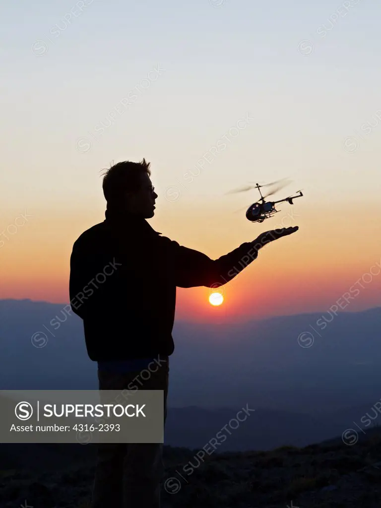 A man launches a radio controlled helicopter at sunset.