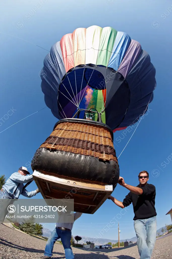 A ground crew maneuvers a hot air balloon after a successful flight.