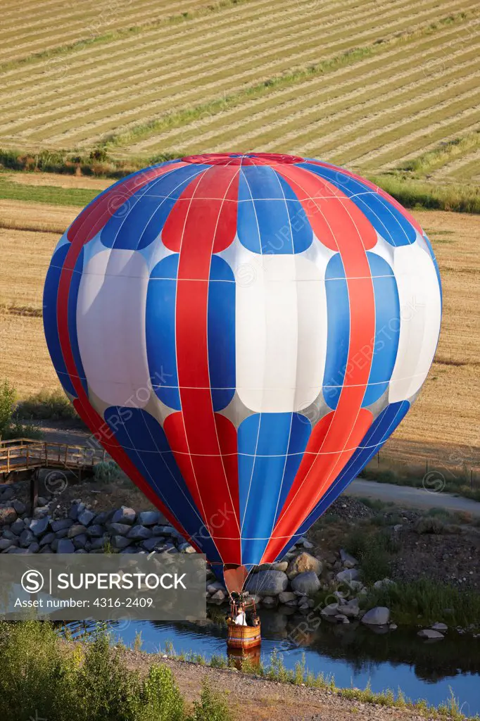 An aeronaut, or hot air balloon pilot, expertly touches his hot air balloon down on a small stream in Gardnerville, Nevada.
