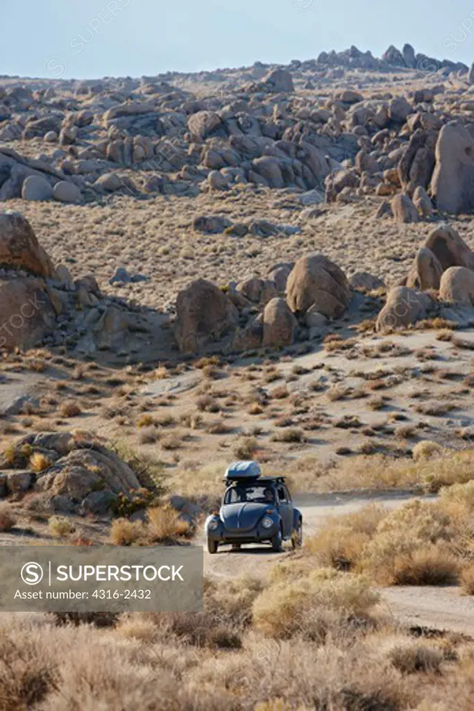 A vintage Volkswagen Beetle plies a dirt road amid boulders in California's Alabama Hills, below Mount Whitney, in the Sierra Nevada mountains, near the town of Lone Pine.