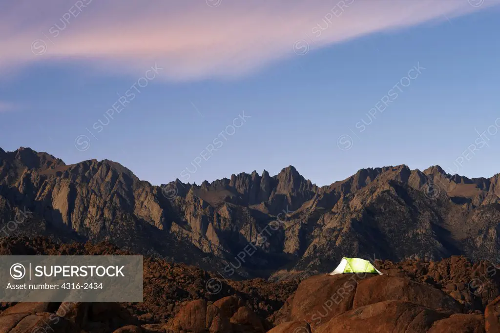 A tent stands atop a large boulder in the Alabama Hills of California, below Mount Whitney and surrounding peaks of the Sierra Nevada Mountains,  near the town of Lone Pine.