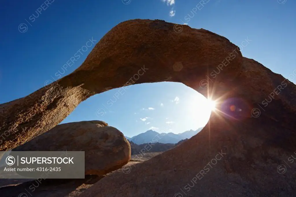 A natural arch in California's Alabama Hills frames peaks near Mount Whitney in the Sierra Nevada Mountains, near the town of Lone Pine. A natural arch demonstrates processes of geomorphology and physical geography.