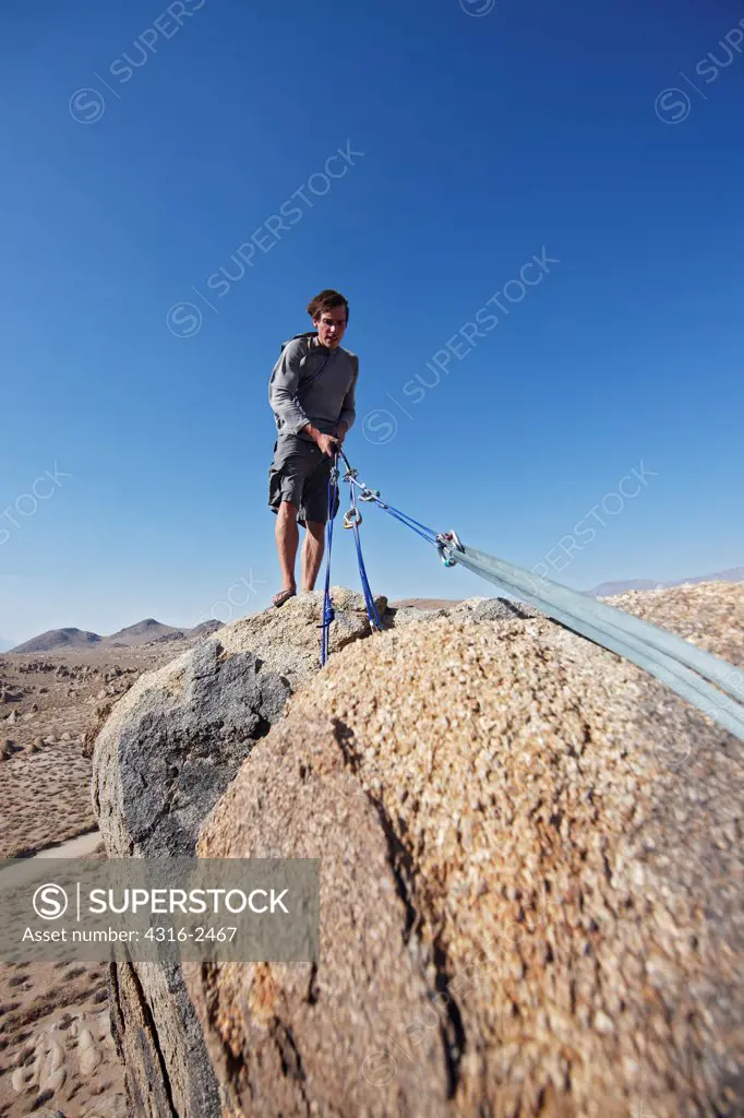 A climber sets up a rope in preparation to rappel down the face of a cliff in California's Alabama Hills, below Mount Whitney, near the town of Lone Pine, under the Sierra Nevada mountains.