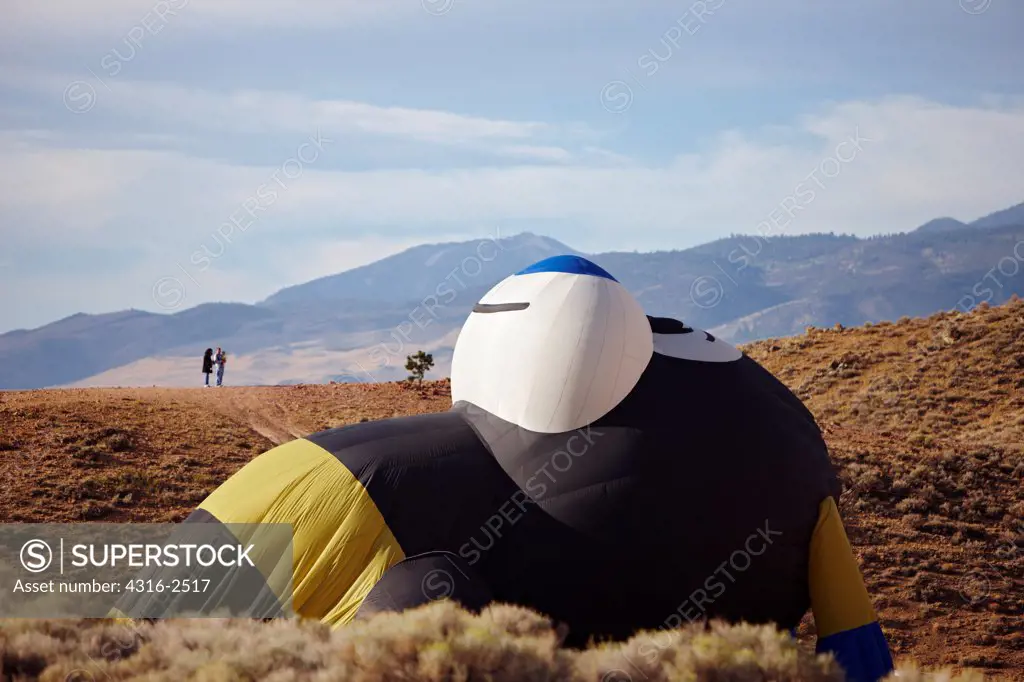 A family of a husband, wife, and young child look on as a bee shaped balloon deflates on a hillside during the Reno Balloon Races, Reno, Nevada.
