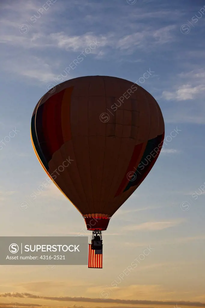 An American flag hangs below a partially silhouetted hot air balloon during the Reno Balloon Races, Reno, Nevada