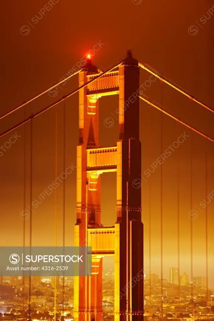 Pre-dawn view of the north tower of the Golden Gate Bridge, under a thick deck of fog.