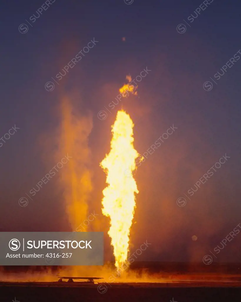 Fierce Updrafts From a Natural Gas Well Fire Lifts a Dust Devil into the Night Sky as a Full Moon Rises in the Distance