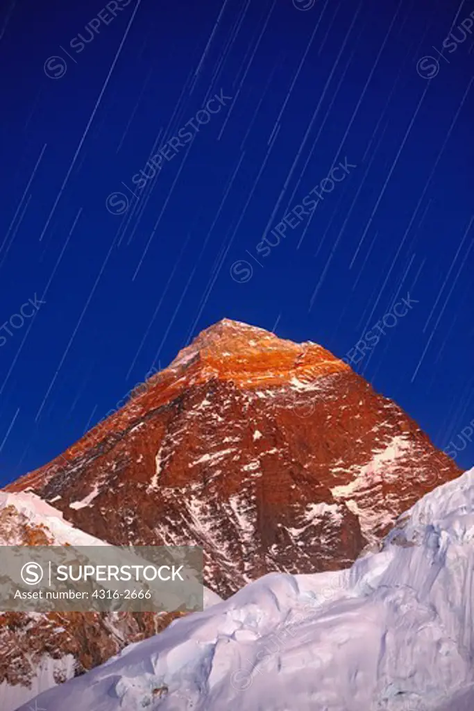 The last of the day's dusk light reflects off of the summit pyramid of Mount Everest, the highest mountain in the world.
