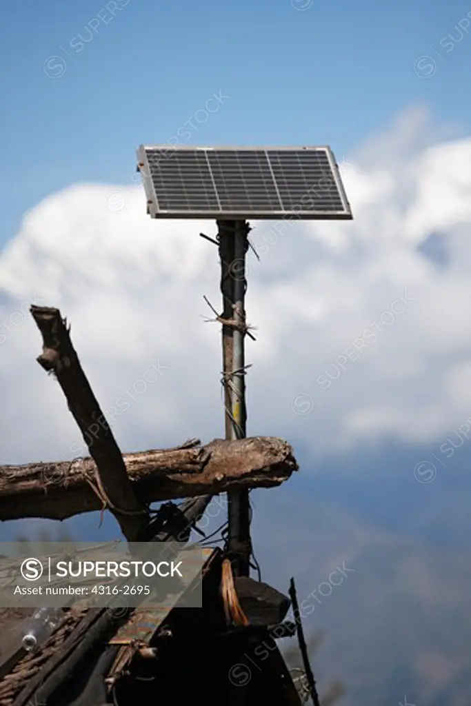 A small solar panel atop a roof in Mure Village, in eastern Nepal, enables a villager a modest amount of electricity when combined with a deep cycle battery and an inverter.