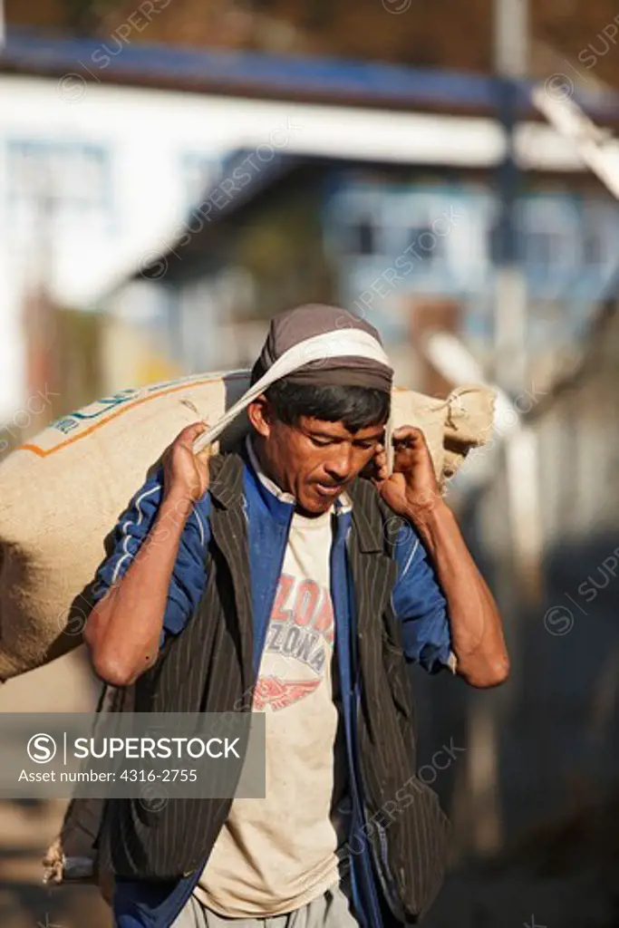 A Nepalese man carries a heavy load of rice, Lukla, Nepal.
