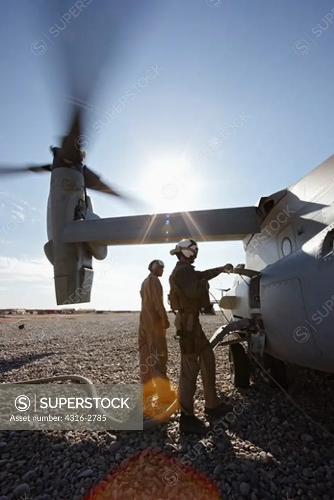 U.S. Marine ground crew refuel an idling MV-22 Osprey at a combat outpost in the Helmand Province of southern Afghanistan.