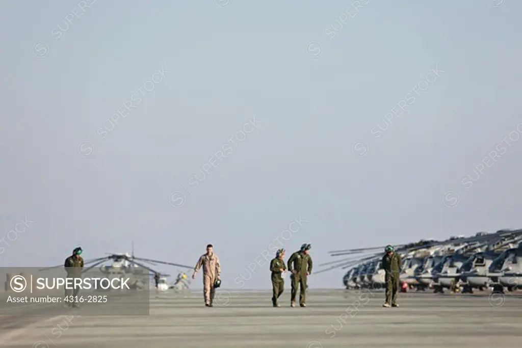 U.S. Marine aviation crewmen inspect a taxiway at Camp Bastion, Helmand Province, Afghanistan, for debris that can be sucked into engine intakes and damage a turbine engine.