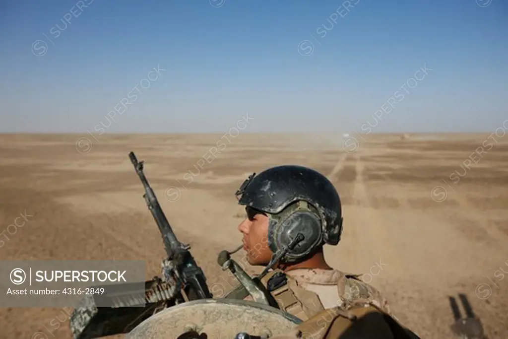 A U.S. Marine scans the distance from atop an LAV-25 during a combat operation on the flat, open desert terrain of Afghanistan's southern Helmand Province.