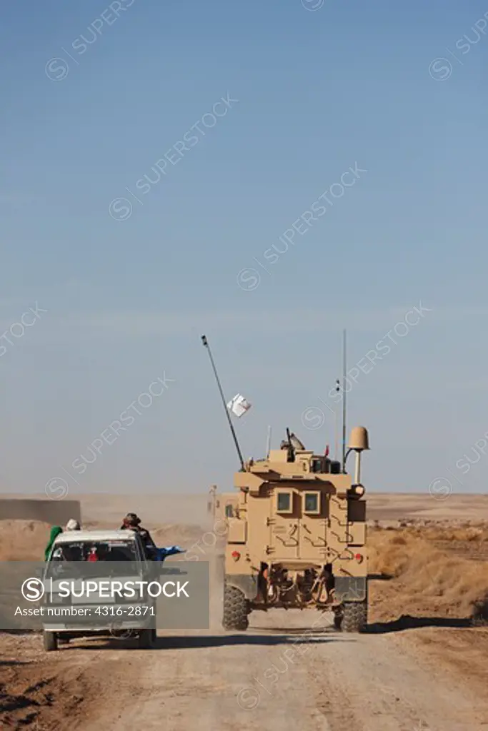 A U.S. Marine MRAP, or Mine Resistant Ambush Protected vehicle passes a local Kia Bongo truck in southern Afghanistan's Helmand Province.