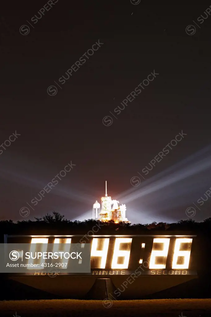 The space shuttle Endeavour, prepared for launch on pad 39A, glows behind a sign counting down the hours until liftoff.