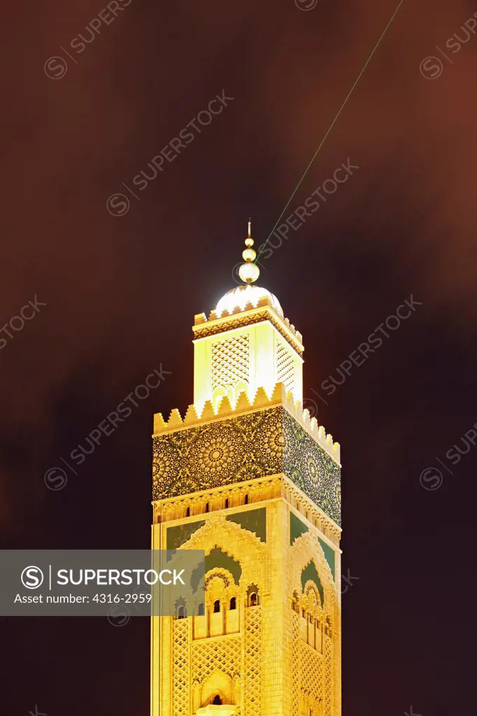 Nighttime view of the upper portion of the Hassan II Mosque's minaret, the tallest minaret in the world at 210 meters high. The laser on the upper minaret emits a green beam which points towards Mecca. The mosque is the tallest structure in Morocco, and was built on reclaimed land overlooking the Atlantic.