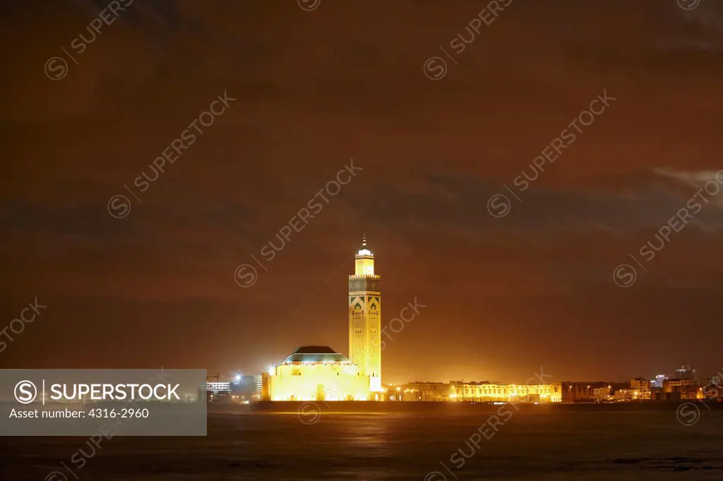 Nighttime view of the Hassan II Mosque. The minaret is the tallest in the world at 210 meters high. The laser on the upper minaret emits a green beam which points towards Mecca. The mosque is the tallest structure in Morocco, and was built on reclaimed land overlooking the Atlantic.