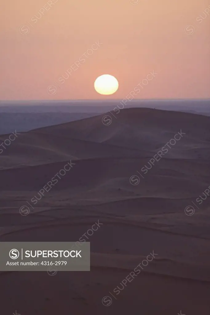 Morning view of the rising sun over a cleft in sand dunes in Erg Chegaga, interior Sahara Desert, Morocco.
