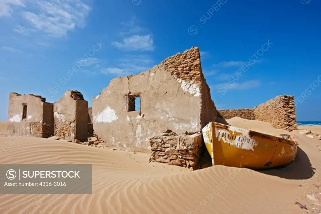 The sand is slowly taking over an abandoned stone building and boat near Tarfaya, southern Morocco.