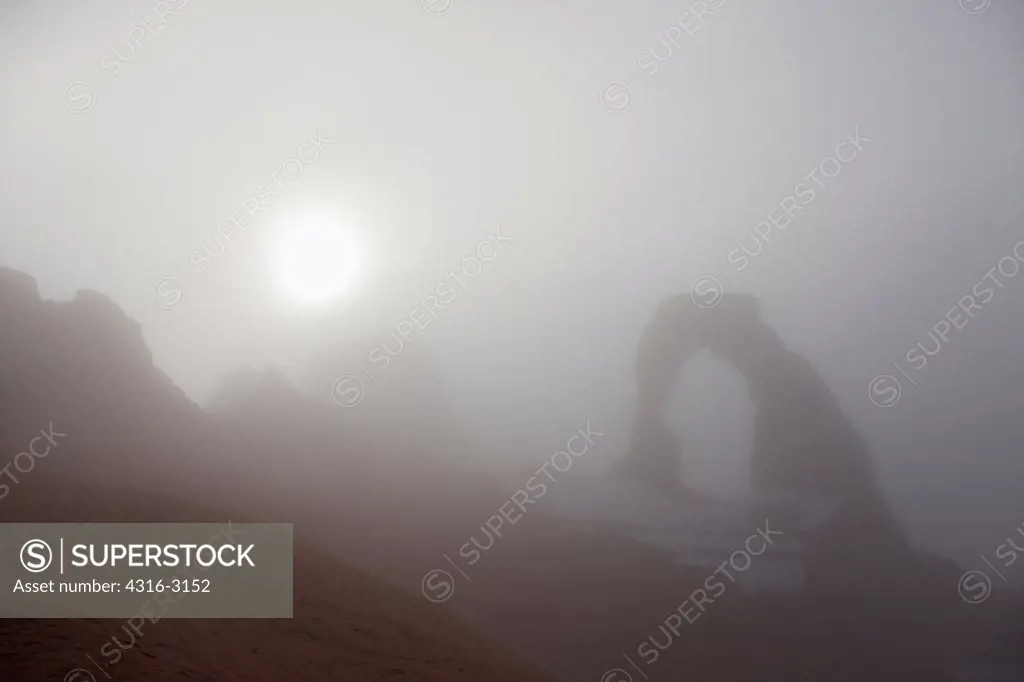 Winter fog visually obscures a view of Delicate Arch, Arches National Park, Utah.