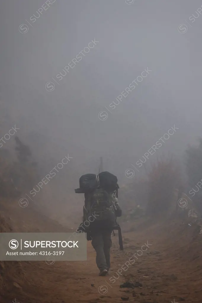 A Nepali Sherpa porter in fog, Namche Bazaar, Nepal.