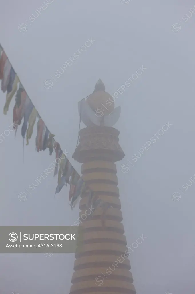 Tibetan Buddhist prayer flags and the spires of a stupa or chorten, Namche Bazaar, Nepal.