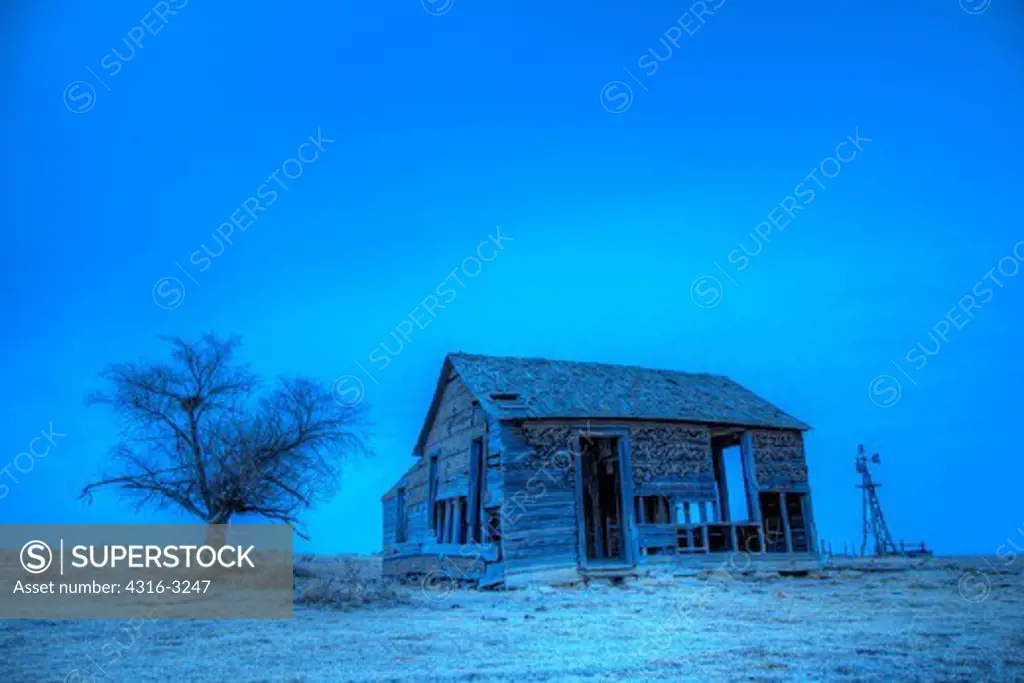 A High Dynamic Range, or HDR, view of a decaying farm house, old windmill, and a dead tree, on eastern Colorado's plains.