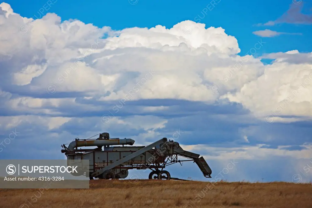 A 1930s era McCormick-Deering threshing machine, also called a thresher, partially silhouetted by storm clouds on Colorado's eastern plains.