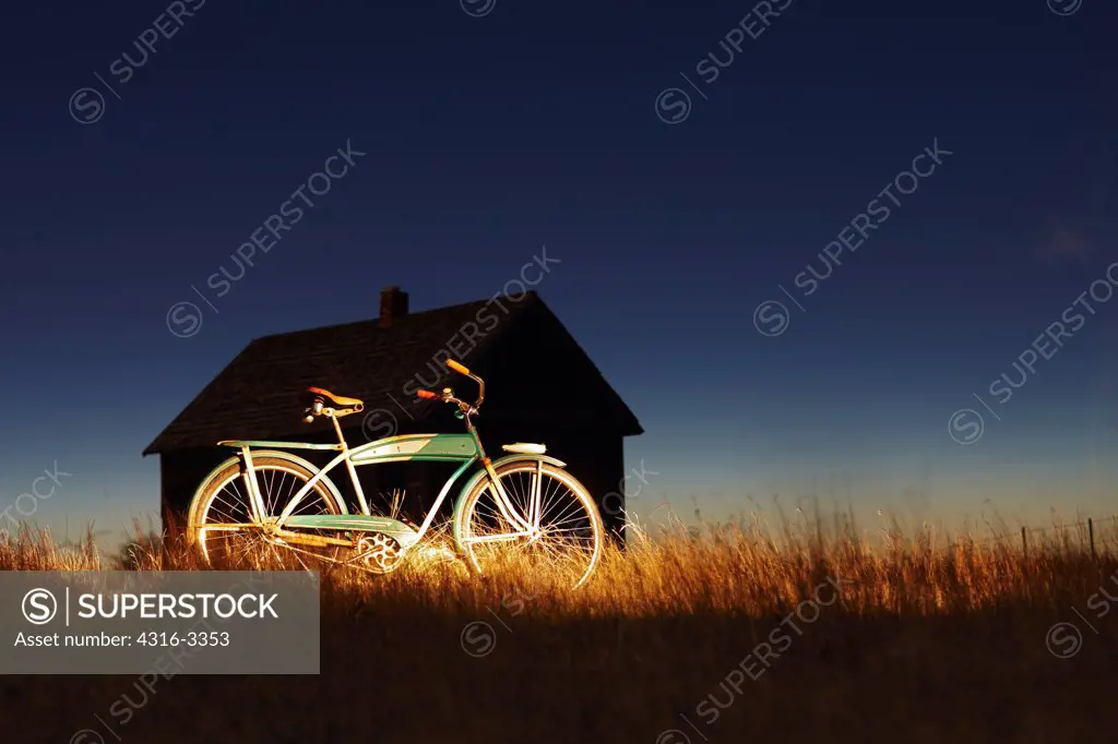 A 1950s era bicycle in front of the silhouette of an abandoned school house at Buckingham, Colorado.