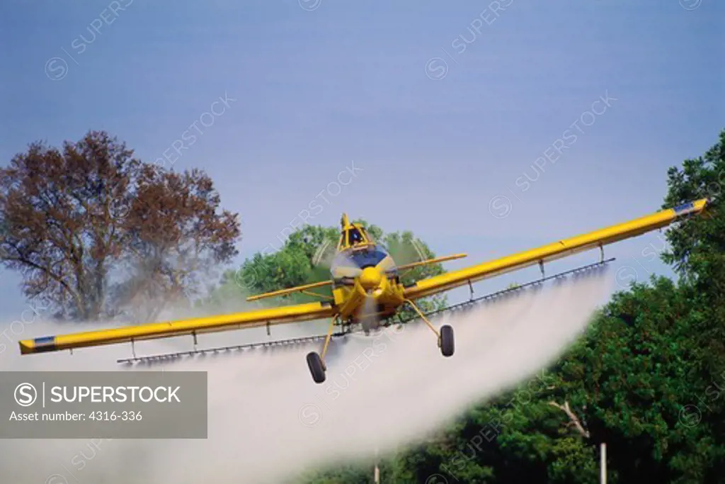Crop Duster Zooms Above a Tomato Field Leaving Fertilizer in its Wake