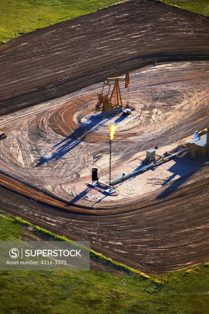An aerial view of an oil well pump jack and a flare stack, which burns off excess natural gas, on eastern Colorado's plains.