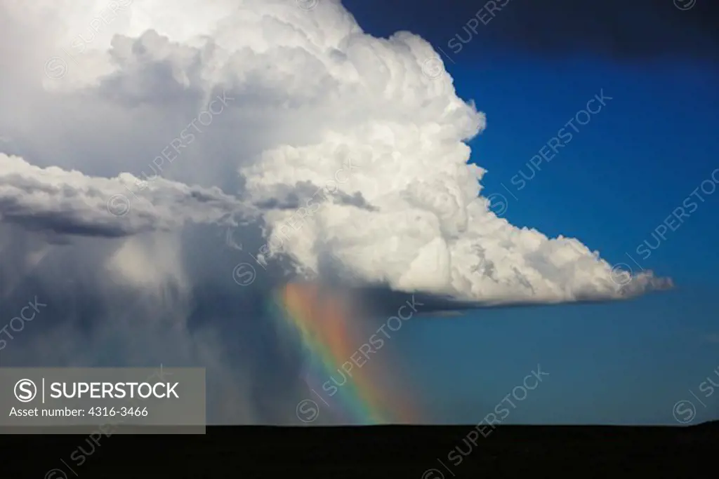 Cumulonimbus, or thunderhead, over sheets of rain and rainbow.