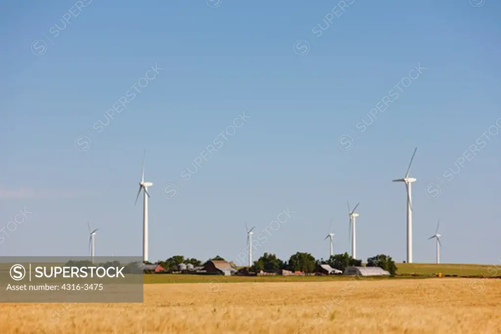 Ranch with a backdrop of a line of wind turbines.