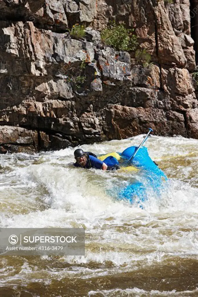 Raft and rafter stranded in rapids on Colorado's Cache la Poudre River.