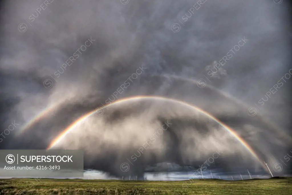 Double rainbow and thunderstorm over wind farm, high dynamic range, or HDR image.