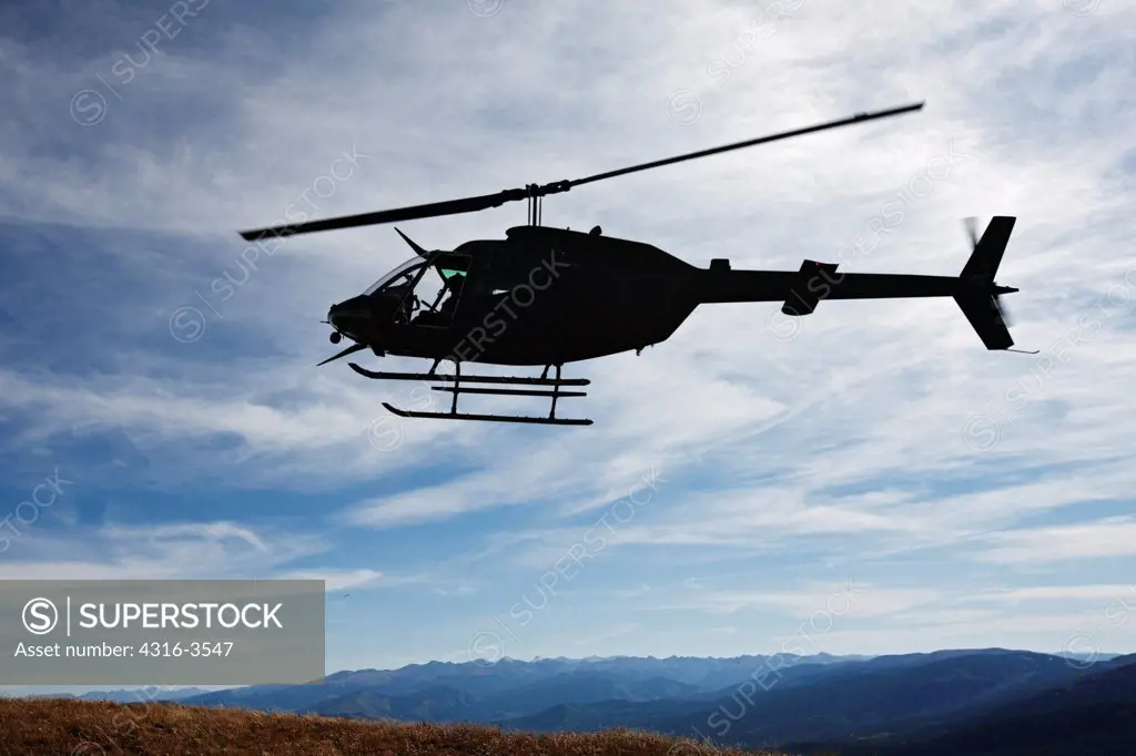 Silhouette of a U.S. Army National Guard OH-58 Kiowa in Colorado's Rocky Mountains.