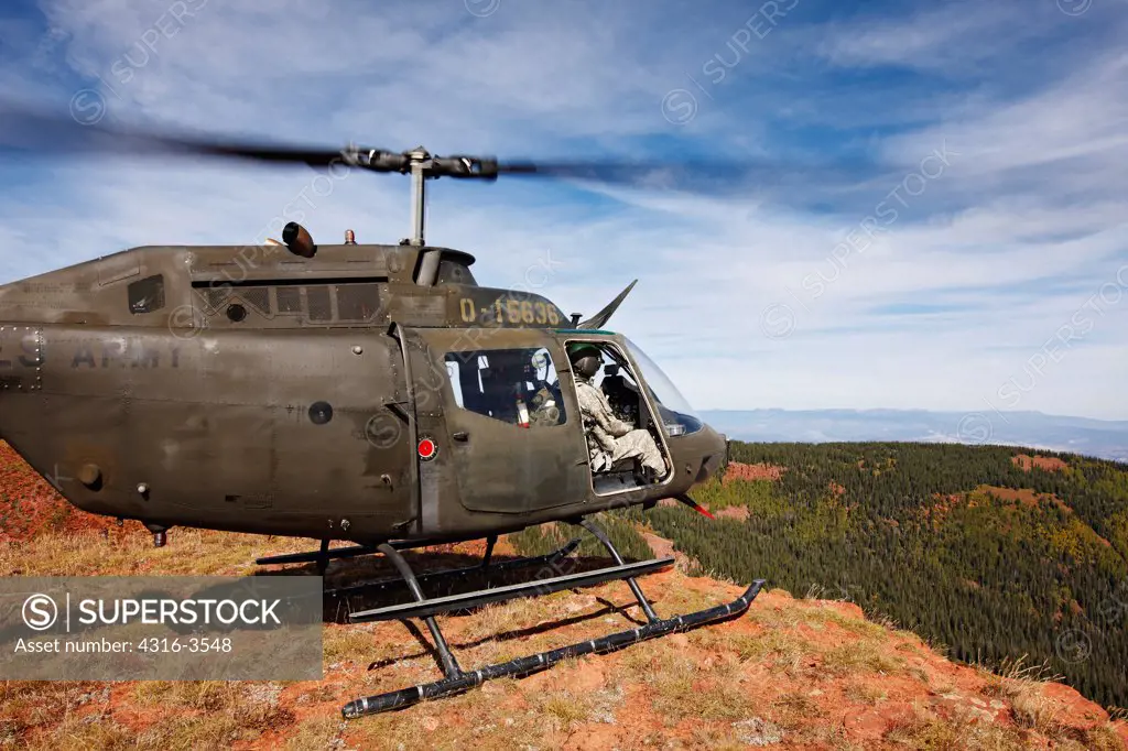 An OH-58 Kiowa, of the Colorado Army National Guard, idles at the edge of a cliff at 11,000 feet in Colorado's Rocky Mountains.