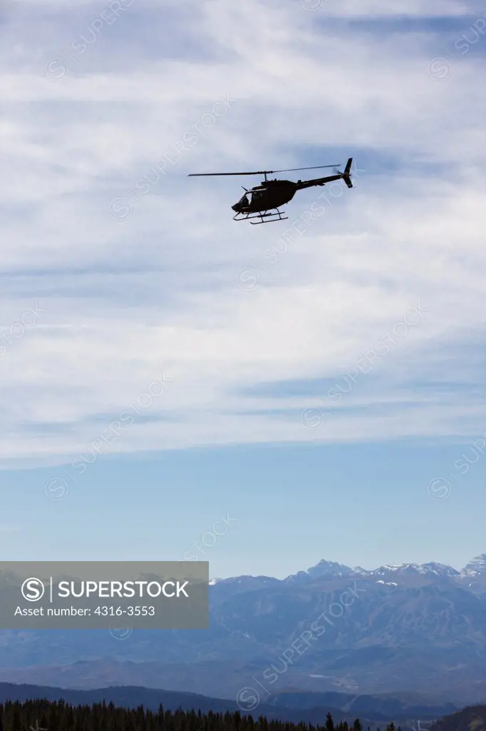 Silhouette of a U.S. Army National Guard OH-58 Kiowa above Colorado's Rocky Mountains.