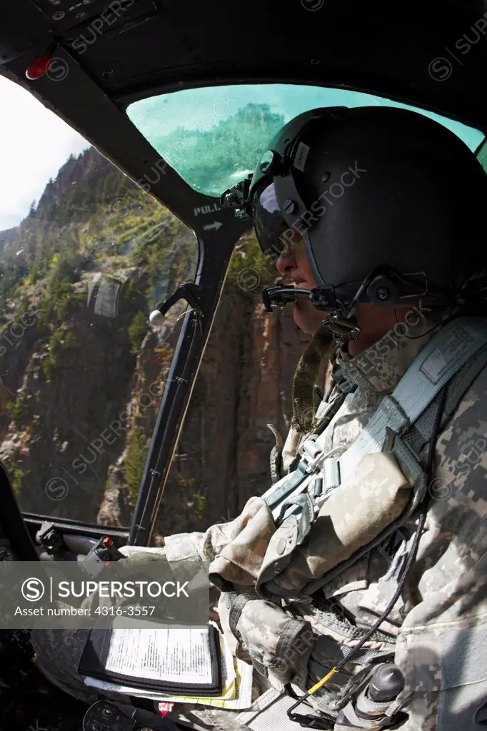 Cockpit view of a pilot of a Bell OH-58 Kiowa while flying in a deep canyon in Colorado's Rocky Mountains.