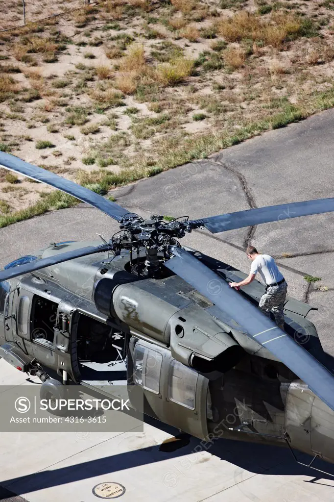 Aerial view of an aircraft maintainer working on a Sikorsky UH-60 Blackhawk helicopter.