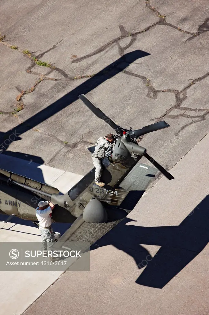 Aerial view of aircraft maintainers working on a Sikorsky UH-60 Blackhawk helicopter.